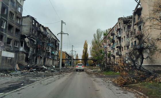 Автомобиль ООН проезжает по пострадавшему от обстрелов городу Украины.
